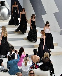 the models are walking down the runway in black and white dresses, while others watch