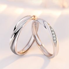 two white gold wedding rings with diamonds on them, against a light colored background that looks like snowflakes