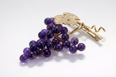 "The 14kt. gold One Leaf and Vine Brooch has a large leaf and a gold runner wire on an 1 1/8\" long vine. The grape cluster has 29 4mm. round natural dark Amethyst gemstones hand mounted to a 14kt. gold grape stem. That is over 3 1/2 carats total weight of Amethyst gemstones! The Cabernet Leaf has a lot of engraved detail as well as engraved detail on the grape stem. The pin on the back is a hinged pin stem with a joint and catch. Overall actual size of this piece is 1 1/2\" tall by 1 1/8\" wide Luxury Purple Brooches For Formal Occasion, Elegant Amethyst Brooches For Wedding, Elegant 14k Yellow Gold Brooches, Luxury 14k Gold Brooch Jewelry, Elegant 14k Yellow Gold Brooch, Elegant Gold Amethyst Brooches, Elegant Purple Brooches For Anniversary, Formal 14k Gold Brooch Jewelry, Amethyst Brooch For Anniversary