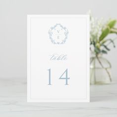 a table number card with a vase of flowers in the background