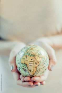 a person holding a small globe in their hands with the world on it's surface