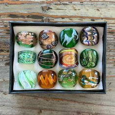 a box filled with lots of different types of glass rocks on top of a wooden table