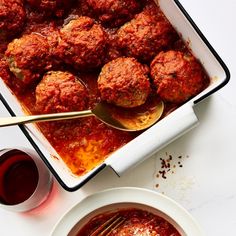 meatballs and sauce in a pan on a table with a spoon next to it