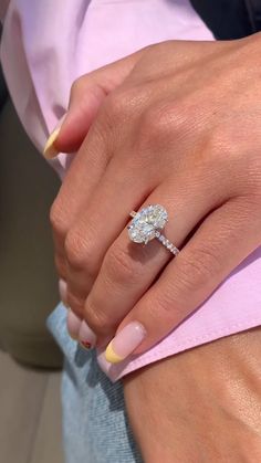 a woman's hand with a yellow and white manicure holding a diamond ring