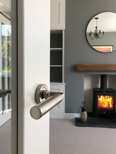 an open door leading to a living room with a fire place in the corner and a mirror on the wall