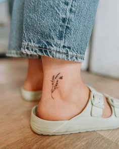 a woman's foot with a small flower tattoo on the side of her ankle