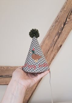 a hand holding a party hat with a turkey design on the front and a pom pom at the top