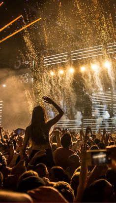 a woman standing on top of a stage surrounded by confetti and fireworks in the air