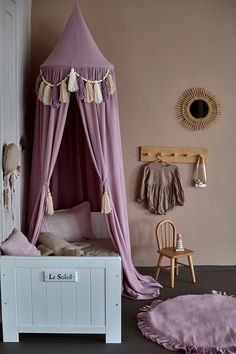 a pink canopy bed sitting next to a wooden chair in a child's room