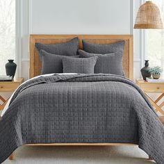 a bed with grey sheets and pillows in a room