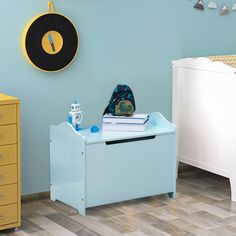 a baby's room with blue walls and wooden floors, including a yellow dresser