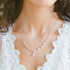 a woman wearing a white lace top and necklace