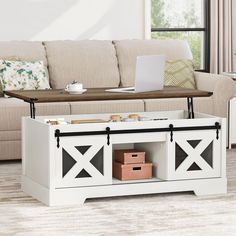 a living room with a couch, coffee table and laptop on top of the entertainment center