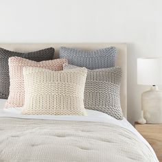 a bed topped with lots of pillows next to a night stand