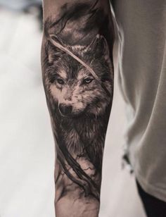 a man's arm with a wolf tattoo on it and an arrow in the middle