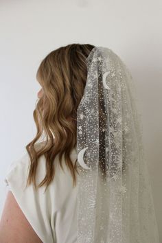 the back of a woman's head wearing a veil with stars and moon designs on it