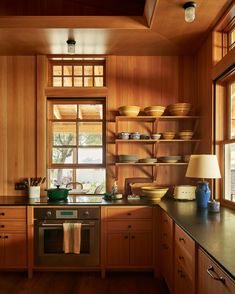 a kitchen with wooden cabinets and an oven in the center is lit by two lamps