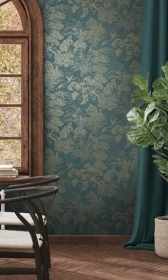 a room with a chair, table and potted plant on the floor in front of a window