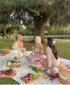 three women sitting at a picnic table with food and drinks