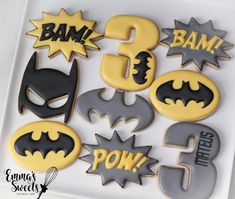 decorated cookies in the shape of batman's numbers and symbols on a white plate