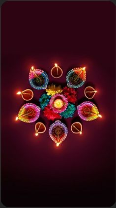 colorful diya with lit candles and flowers on dark background for diwali festival