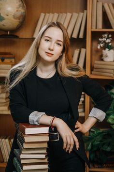 a woman standing next to a stack of books