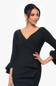 a woman in a black dress posing with her hands on her hips and one hand on her hip