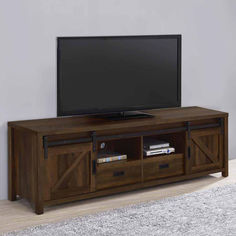 a flat screen tv sitting on top of a wooden entertainment center next to a white rug