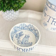 a blue and white bowl sitting on top of a table next to a potted plant