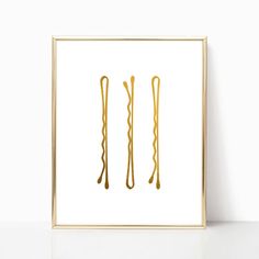 two gold colored hair ties are hanging on a white wall in front of a framed photograph