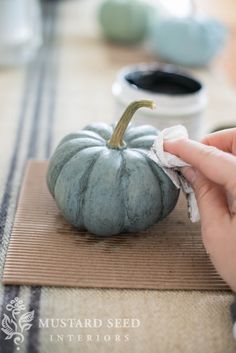 a person is cleaning a small blue pumpkin on a place mat with a cloth around it