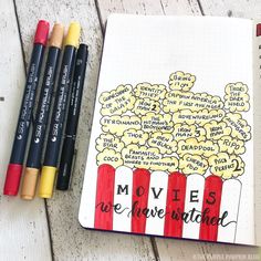 a notebook with some writing on it next to three markers and two pencils in front of them