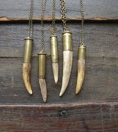 four necklaces with different types of horns hanging from chains on a wooden surface,