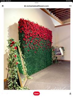 a green wall covered in red flowers next to a mirror