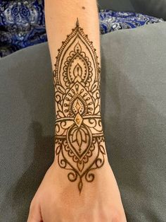 a woman's hand with a henna tattoo on her wrist and the arm