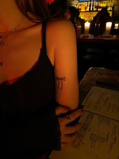 a woman sitting at a bar with a tattoo on her arm