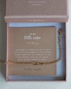 a little sister bracelet in a pink box with a gold plated chain attached to it