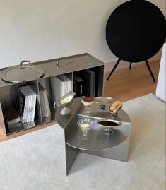 a silver coffee table sitting on top of a white rug next to a book shelf