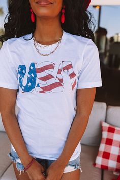 – Perfect for the festive season – Lightweight cotton material – Cute red, white and blue graphic font on the front – Round neckline – Short loose sleeves – Slouched silhouette that falls into a straight hemline White Cotton T-shirt With American Flag Print, Patriotic White T-shirt For Spring, Red Flag Print T-shirt, White Americana T-shirt For 4th Of July, White Crew Neck Top For Memorial Day, White American Flag Top For Memorial Day, White Americana Tops For Summer, American Style White Tops For 4th Of July, White Americana Style Tops For Summer