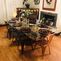 a dining room table with chairs and plates on it in front of a fire place