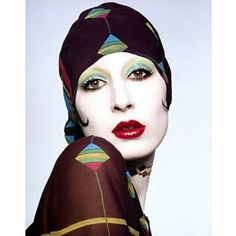 a woman with green eyeshades and red lips wearing a head scarf on top of her head