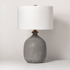 a gray ceramic table lamp with a white shade