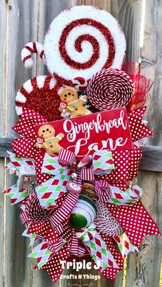 a christmas wreath made out of candy canes and other holiday decorations on a wooden fence