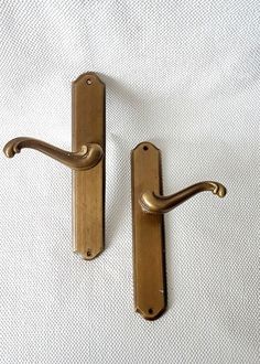 two brass door handles on a white fabric background, one is open and the other is closed