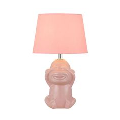 a pink table lamp with a smiling face on the base and a light shade over it