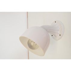 a white light on the side of a wall next to a lamp shade and door