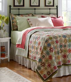 a bed room with a neatly made bed and pictures on the wall above it that says l l bean blooming circles quilt collection