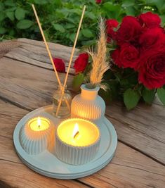 two candles are sitting on a plate next to roses