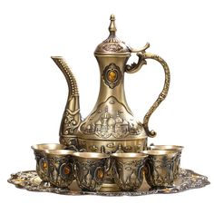 an ornately designed tea set with matching cups and saucers on a silver tray