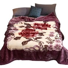 a bed covered in a purple blanket with flowers on it